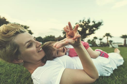 Young Mother and cute little daughter enjoying free time playing outside at backyard on the grass, happy family in nature concept