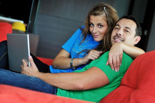 happy young couple have fun and relax at comfort bright apartment and work on laptop computerhappy young couple have fun and relax at comfort bright appartment and work on laptop computer