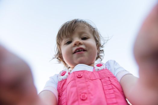 playful cute little girl cheerfully spending time while running in the spacious backyard on the grass