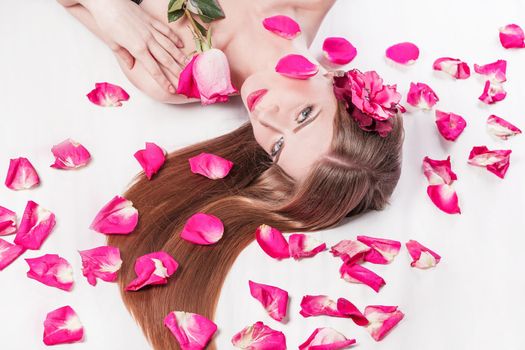 beautiful young woman on rose petals background. photo with copy space