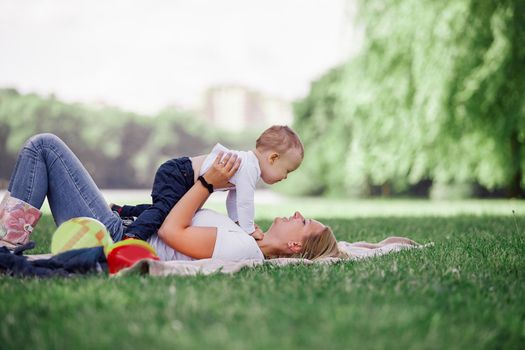 mom and her little son play together, lying on the lawn . photo with copy space