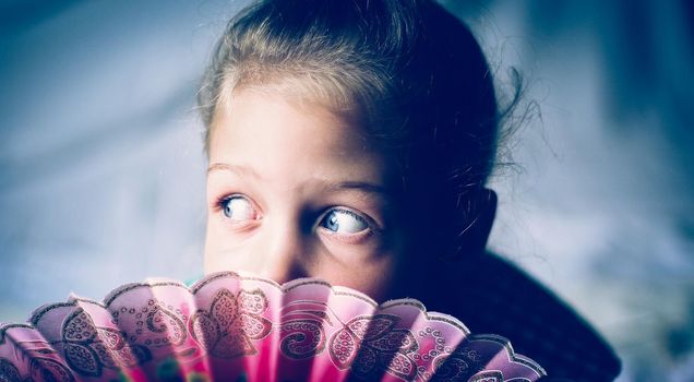 portrait - cute on bright background little girl with a fan .the photo has a empty space for your text
