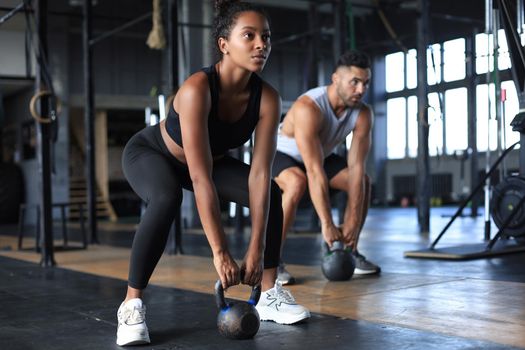 Fit and muscular couple focused on lifting a dumbbell during an exercise class in a gym