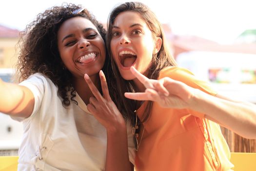 Cute young girls friends having fun together, taking a selfie while sitting at cafe