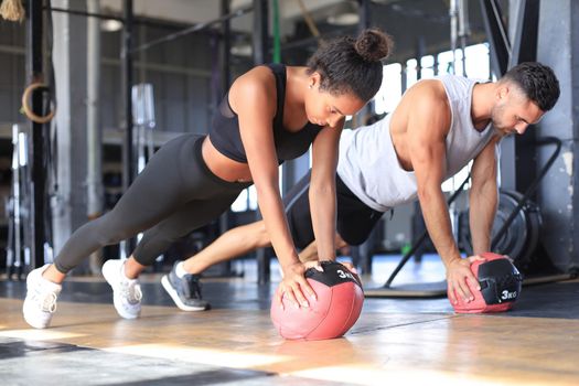 Beautiful young sports couple is working out with medicine ball in gym