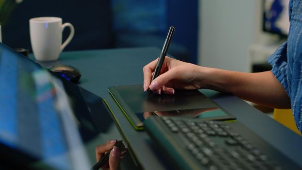 Close up of hand holding stylus on graphic tablet for retouch work. Woman photographer using editing app for pictures retouching at photography studio. Image editor with devices