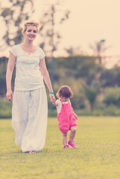 Young Mother and cute little daughter enjoying free time playing outside at backyard on the grass, happy family in nature concept