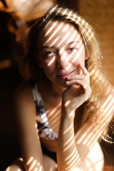 Portrait of young european woman wearing bra, striped shadows. Concept of beautiful female person and home photosession.