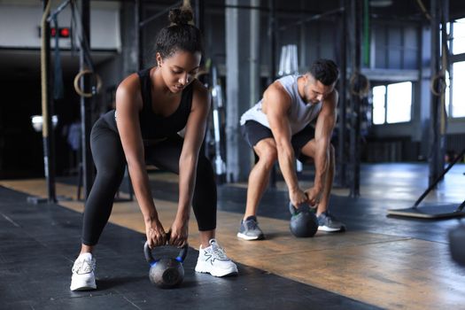 Fit and muscular couple focused on lifting a dumbbell during an exercise class in a gym