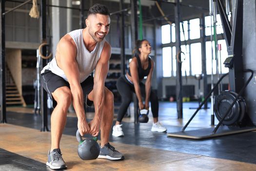 Fit and muscular couple focused on lifting a dumbbell during an exercise class in a gym