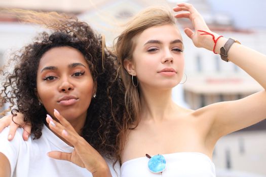 Young smiling hipster women in summer clothes posing on street.Female showing positive face emotions