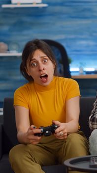 POV of interracial couple playing video game on console in living room. Young multi ethnic people highfive while winning at home. Mixed race partners enjoying fun activity on television