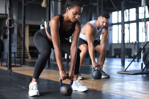 Fit and muscular couple focused on lifting a dumbbell during an exercise class in a gym