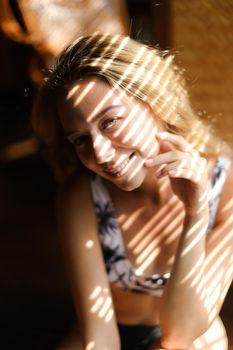Portrait of young smiling woman wearing bra, striped shadows. Concept of beautiful female person and home photosession.