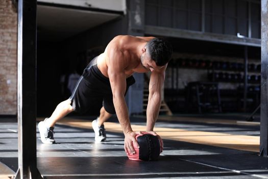 Fit and muscular man exercising with medicine ball at gym