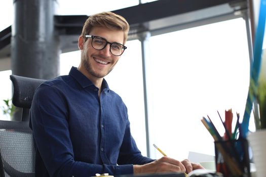 Good looking young business man drawing something while working in the office
