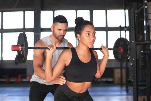 Man and woman with barbell flexing muscles in gym