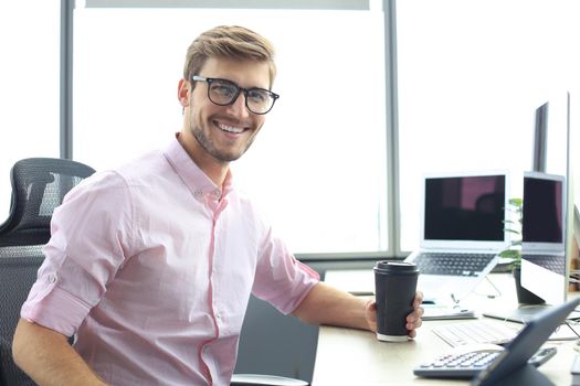 Young modern business man working using digital tablet while sitting in the office