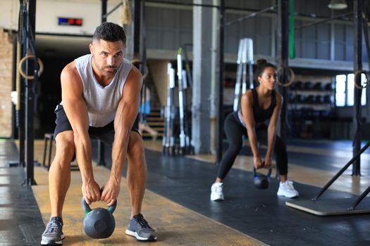 Fit and muscular couple focused on lifting a dumbbell during an exercise class in a gym