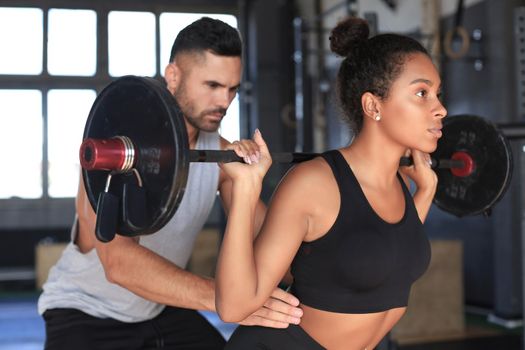 Man and woman with barbell flexing muscles in gym