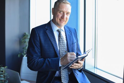Middle aged businessman working and taking notes in his modern office