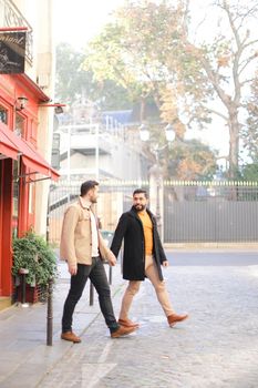 Caucasian gays walking and holding hands in city. Concept of same sex couple and lgbt.