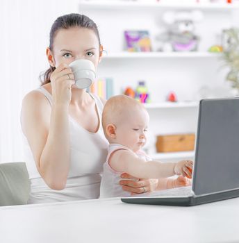 modern young mom with little baby sitting at the Desk.the concept of freelancing