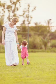 Young Mother and cute little daughter enjoying free time playing outside at backyard on the grass, happy family in nature concept