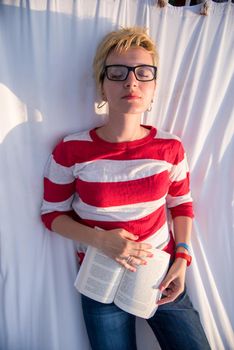 young woman reading a book while relaxing on hammock in a peaceful garden during holiday