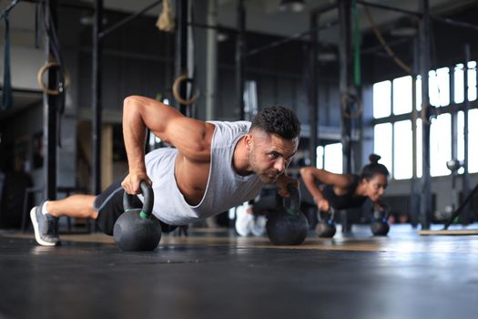 Sporty man and woman doing push-up in a gym