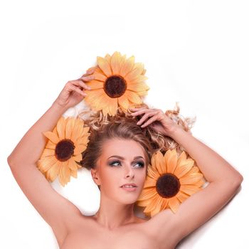 beautiful woman model lying among the flowers of a sunflower. skin care and healthy lifestyle concept