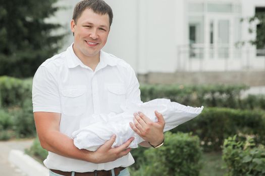 smiling father with his newborn baby standing near the maternity hospital.