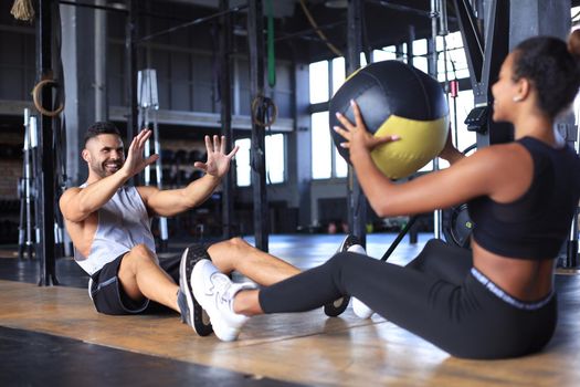 Fit and muscular couple exercising with medicine ball at gym