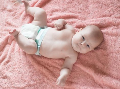 portrait of a pretty baby lying on a pink blanket. photo with space for text
