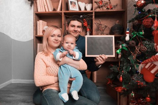 young happy parents showing blank Christmas card . holiday concept