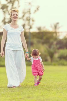 Young Mother and cute little daughter enjoying free time playing outside at backyard on the grass, happy family in nature concept