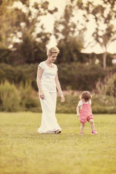 Young Mother and cute little daughter enjoying free time playing outside at backyard on the grass, happy family in nature concept