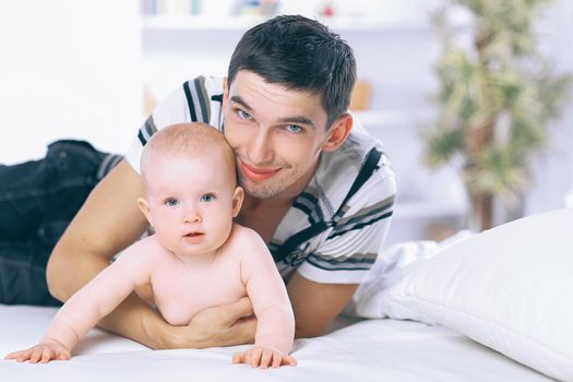 happy young father playing with baby on sofa at home