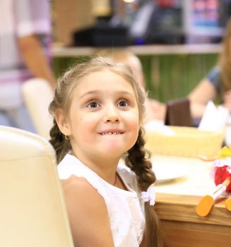happy little girl sitting in a children's caf .the concept of happiness