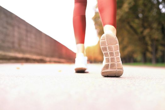 Runner feet running on road closeup on shoe, outdoor at sunset or sunrise