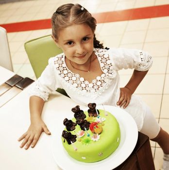 happy little girl looking at cake in her birthday