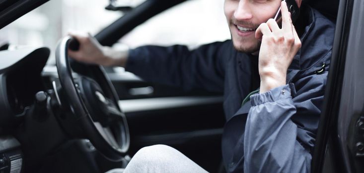 closeup.happy man talking on mobile phone in the car