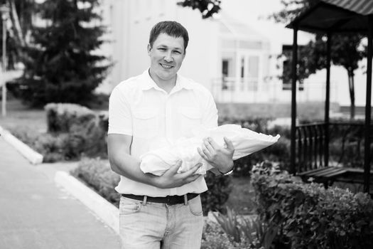 photo in retro style. young happy father with newborn baby standing near perinatal center.