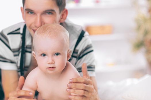 happy young father playing with baby on sofa at home