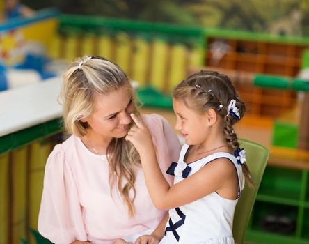 mother and daughter sitting in the children's cafe .the concept of the celebration