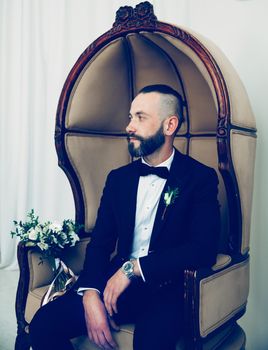 brooding groom waiting for his bride sitting in a chair . people and events