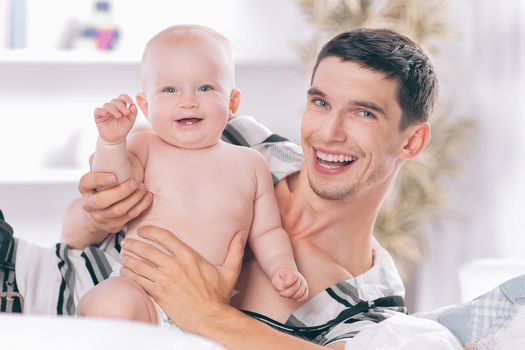 happy young father playing with baby on sofa at home