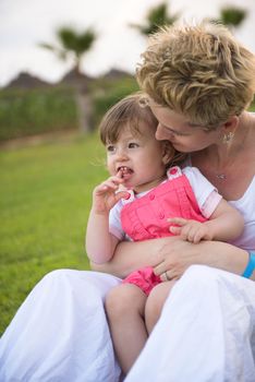 Young Mother and cute little daughter enjoying free time playing outside at backyard on the grass, happy family in nature concept