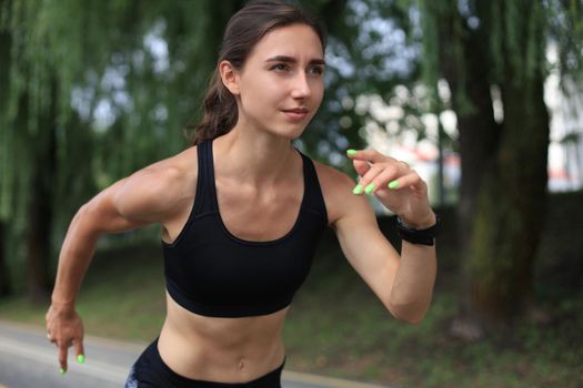 Young woman in sports clothing running while exercising outdoors