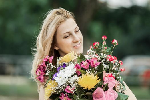 smiling woman with a bouquet of flowers on a blurred background of the Park